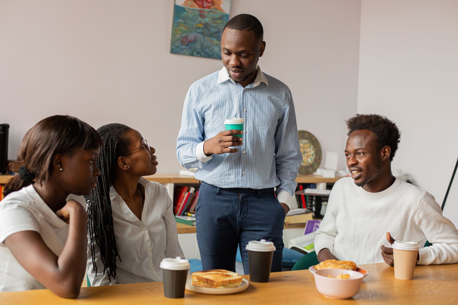 Colleagues talking over coffee and sandwiches at work.