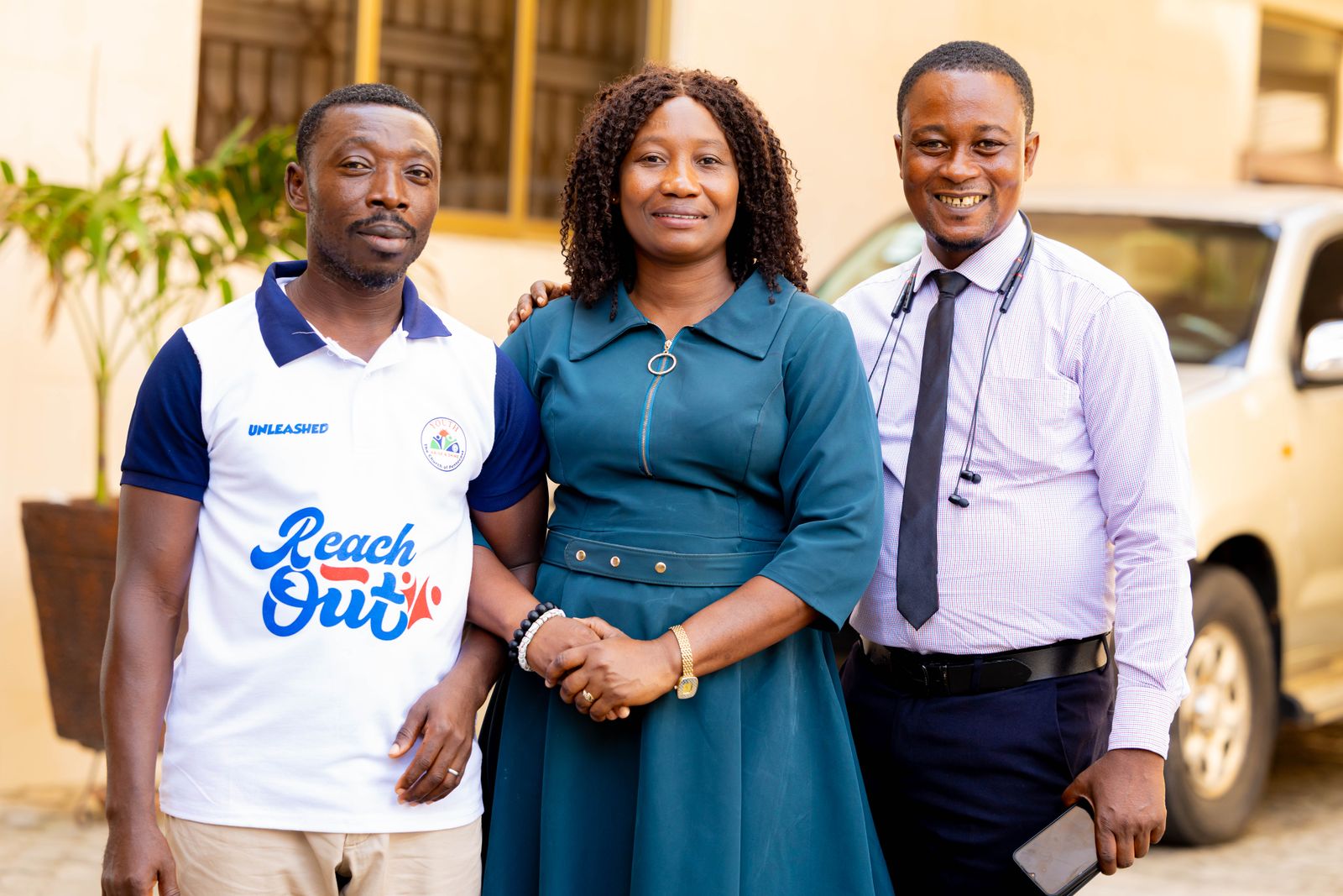 Three colleagues smiling together outside their workplace.